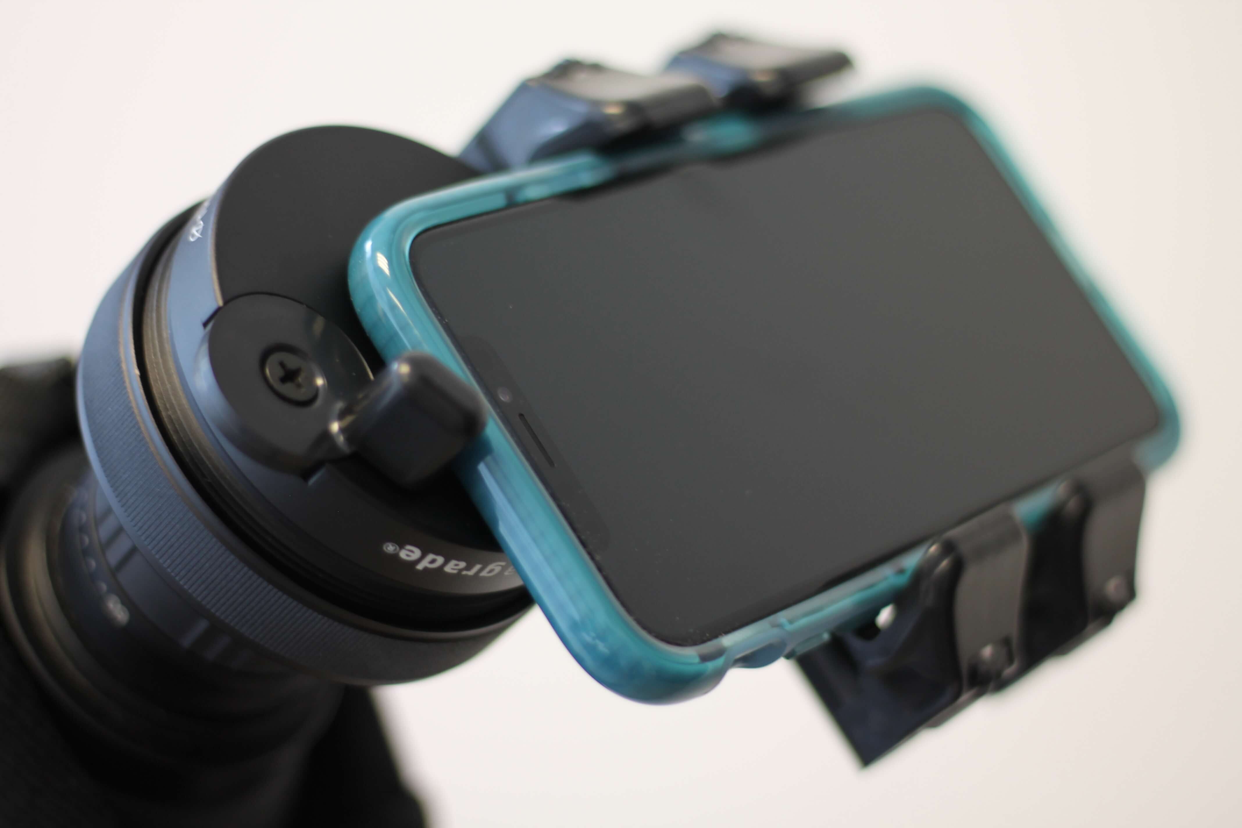 Ein Smartphone in einer blauen Hülle ist sicher auf einem Stativ mithilfe einer speziellen Halterung befestigt.