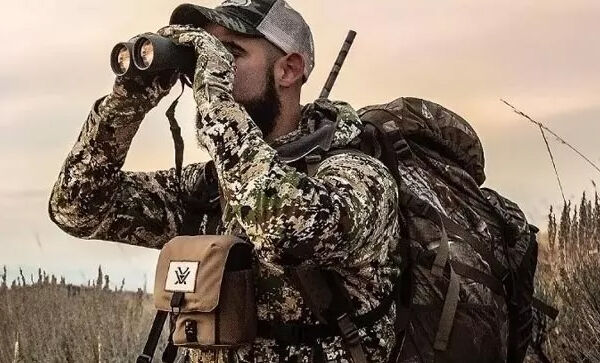 Jäger in Tarnkleidung mit Rucksack nutzt Fernglas in der Natur