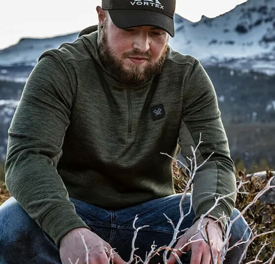 Mann in warmem Pullover und Mütze in einer bergigen Landschaft