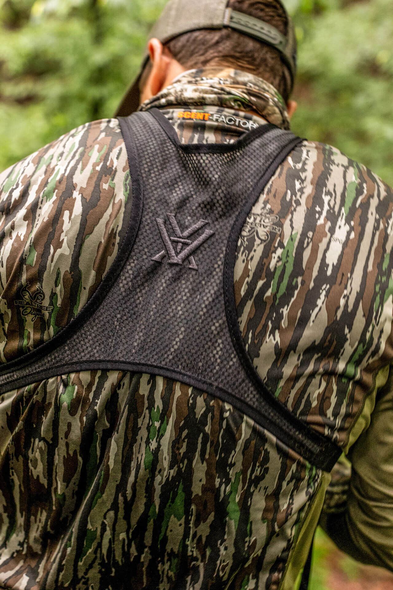 Rückansicht eines Jägers in einer Tarnjacke mit Cap im Wald