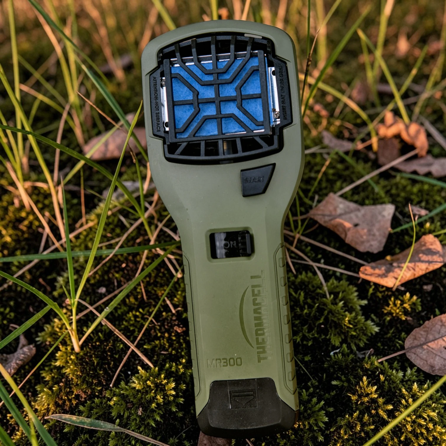 Thermacell MR-300LI PT-19 Mückenabwehr Handgerät in Olivgrün, im Gras platziert, für bis zu 15 m² mückenfreie Outdoor-Schutzzone ohne Spray