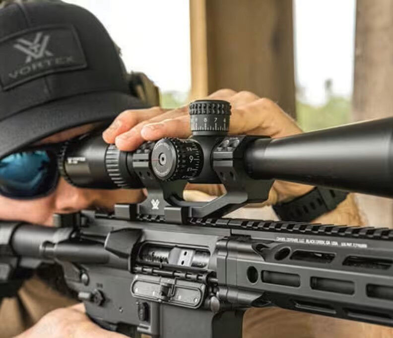 Person zielt durch ein Zielfernrohr auf einem Gewehr auf dem Schießstand
