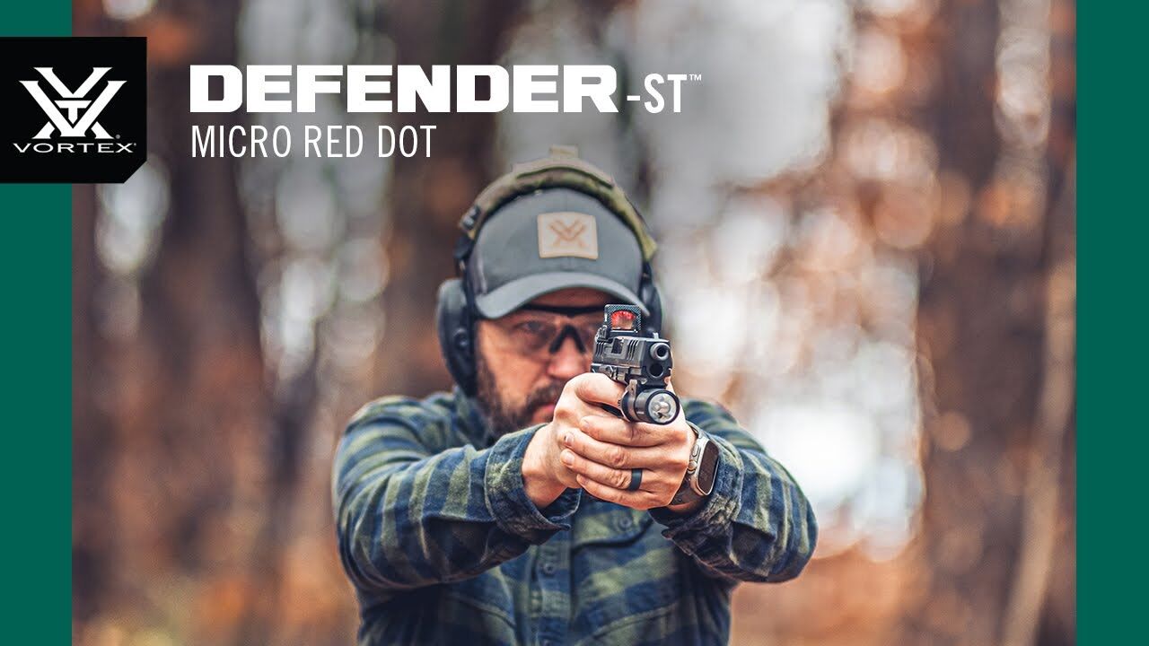 Person mit Gehörschutz zielt mit einer Pistole, ausgestattet mit einem Vortex Defender-ST Micro Red Dot, im Wald.