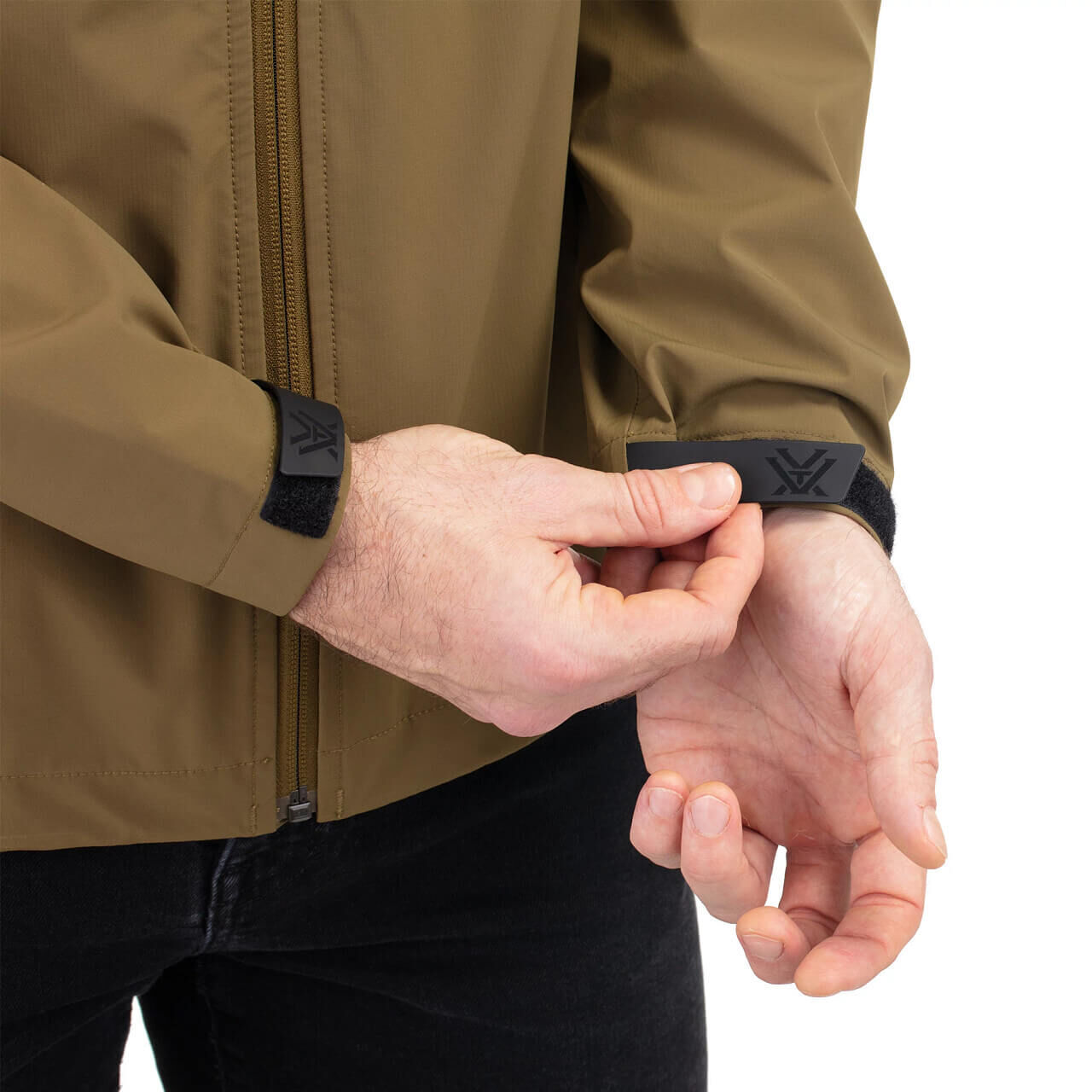 Person passt das verstellbare Bündchen einer braunen Outdoorjacke an