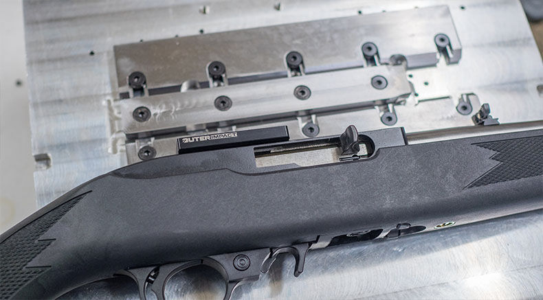 Detailansicht eines Gewehrs auf einer Metalloberfläche mit Montageschienen