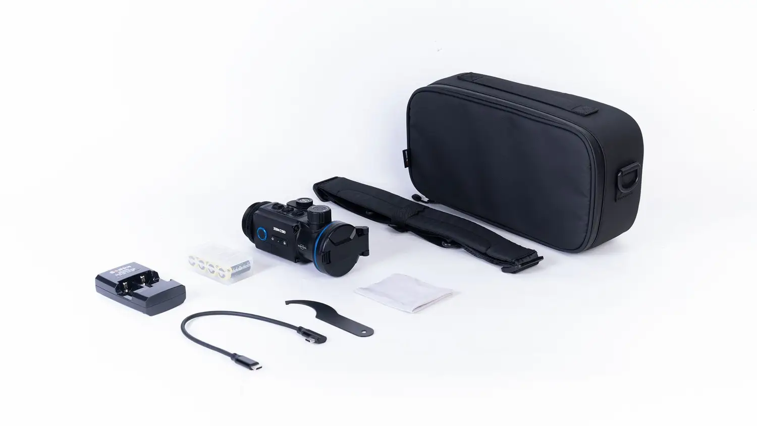 Komplettset eines digitalen Nachtsichtgeräts auf weißem Hintergrund mit Tragetasche, Schultergurt, Ladegerät, Akkus, USB‑Kabel, Werkzeug und Reinigungstuch