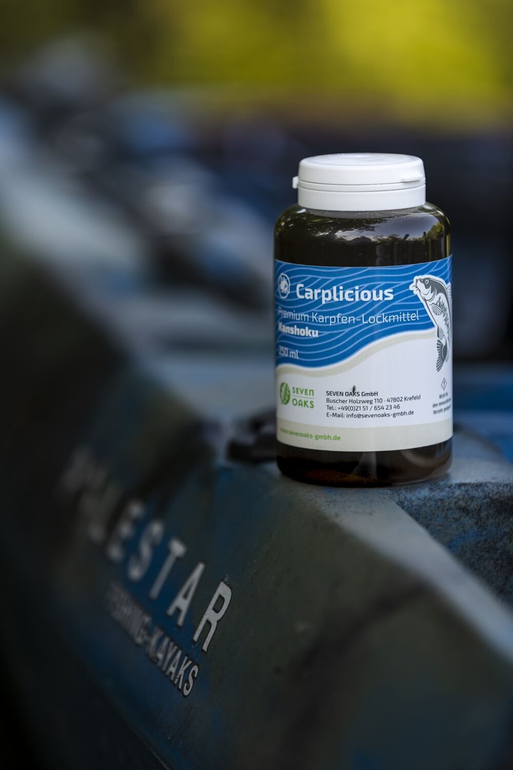 Flasche Carplicious Premium Karpfen-Lockmittel, Kanshoku 250 ml, auf einem Boot