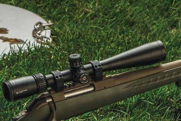 Nahaufnahme eines Zielfernrohrs, das auf einem Gewehr installiert ist, das im Gras liegt