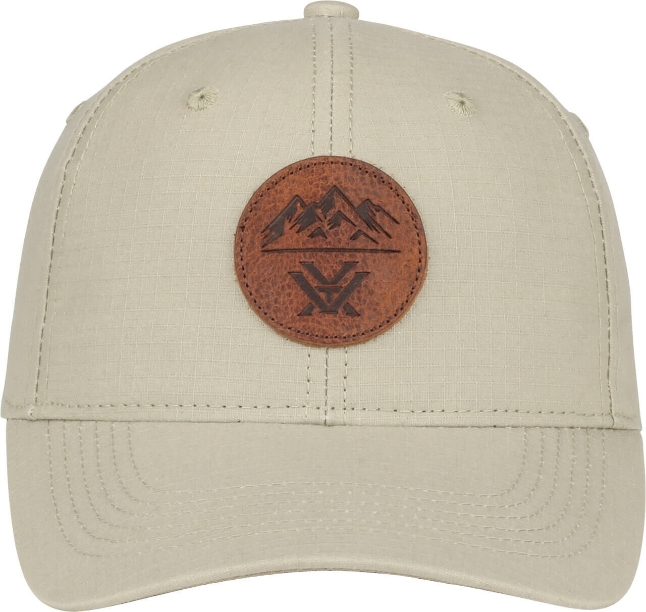 Eine beige Cap mit einem runden Lederaufnäher, der ein Bergmotiv zeigt.