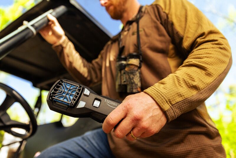 Mann im Outdoor-Einsatz hält ein mobiles Mückenschutzgerät in der Hand, ideal für Jagd, Camping und andere Aktivitäten im Freien