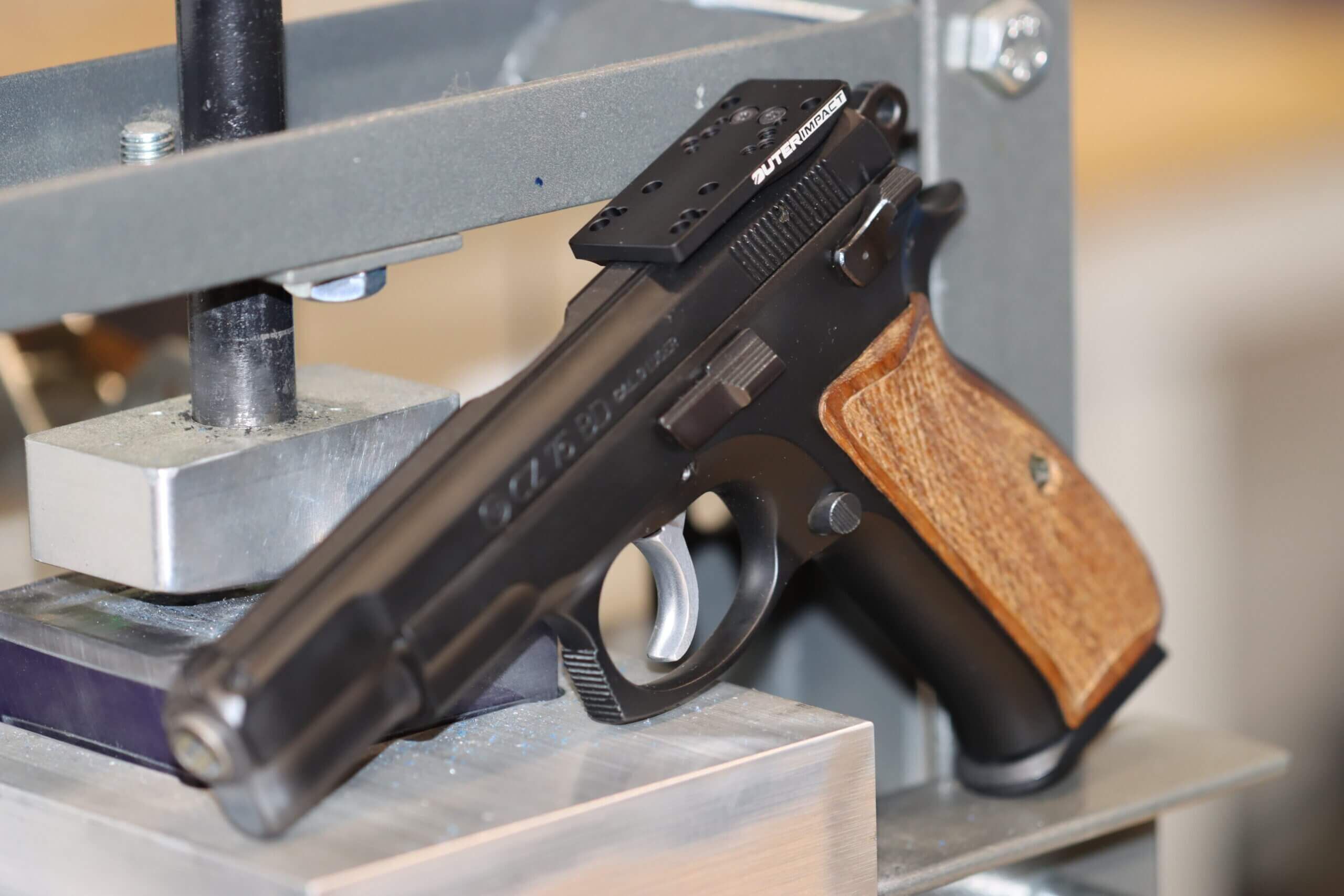 Detailansicht einer modernen Pistole mit Holzgriff und montierter Optik