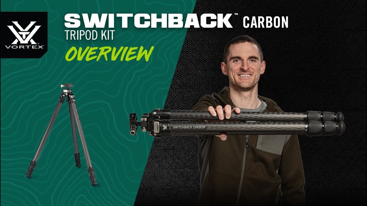Person hält zusammengeklapptes Vortex Switchback Carbon Stativ Kit vor grünem Hintergrund